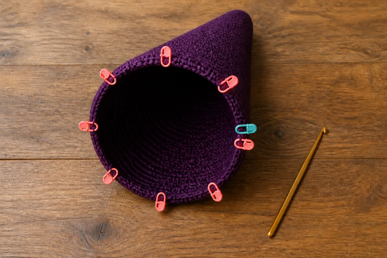 Eight coral sector markers and one teal round marker divide a deep-plum crochet cone