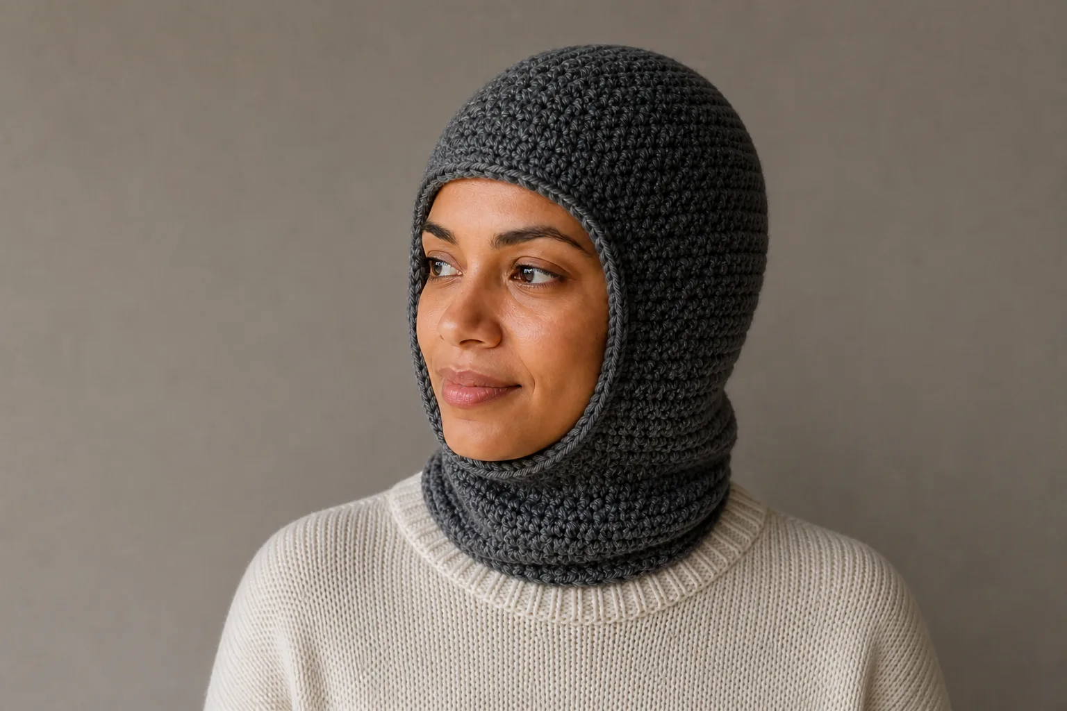 An adult turns their head in profile while wearing the finished charcoal crochet balaclava