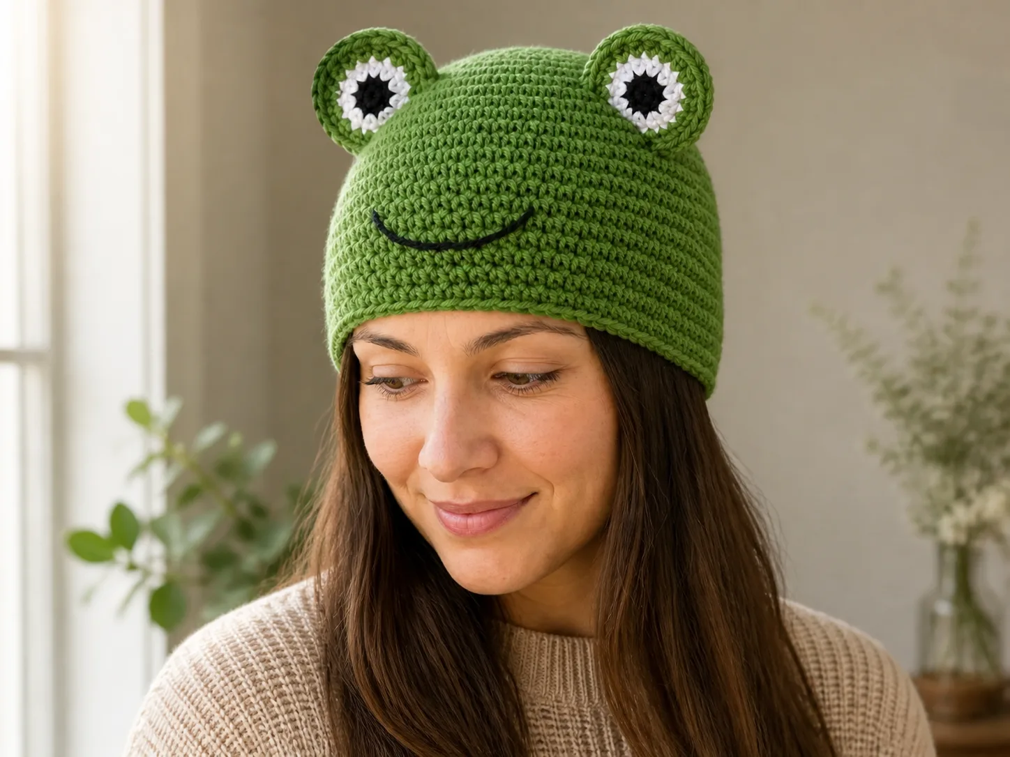 Side-front view of the same adult wearer turning her head in the fitted green frog beanie while both textile eyes remain above the sight line